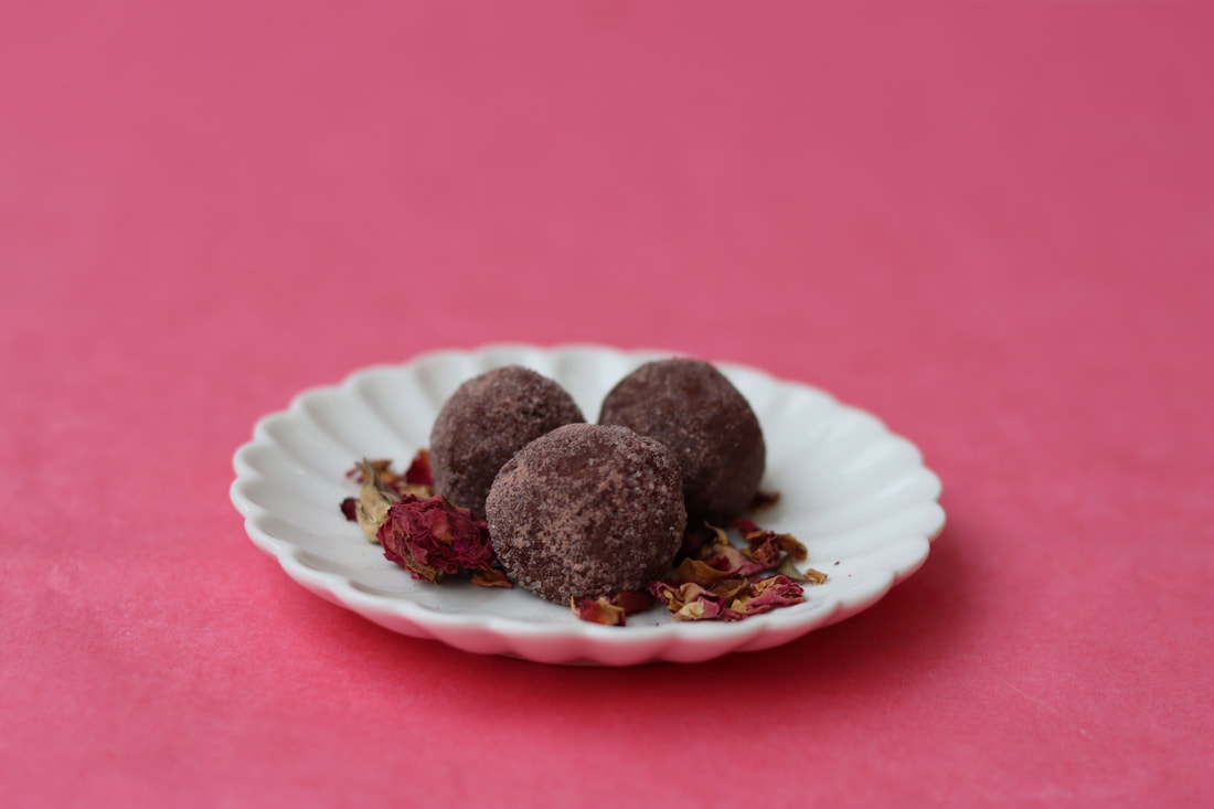 Chocolate-rose truffles on white plate with pink background from Valentine's day event