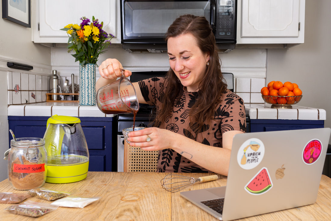 Woman pouring chocolate elixir into mug during virtual elixir workshop