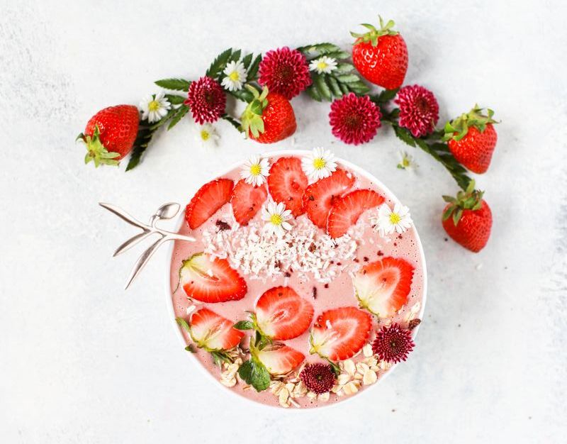 Superfood smoothie with strawberries, coconut and flowers ontop