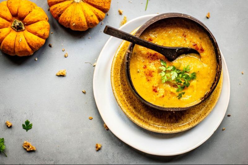 gut healing pumpkin soup in bowl with pumpkin in the corner