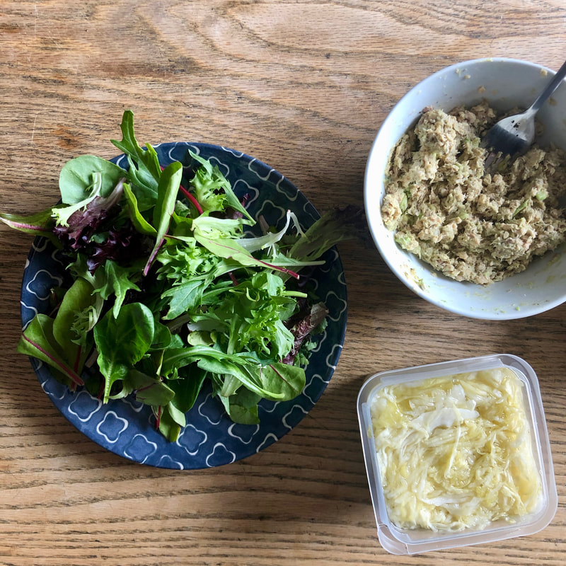 Salmon salad in bowl with side of greens and sauerkraut 