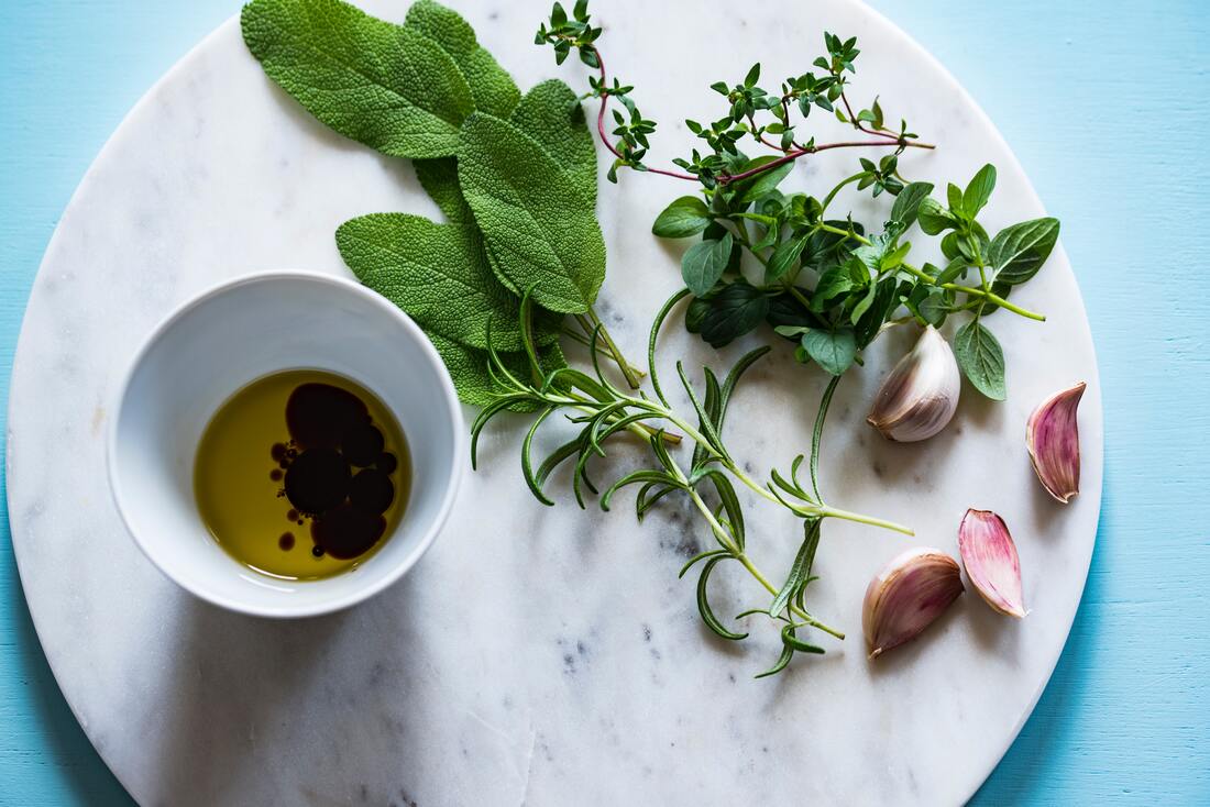 marble plate with fresh herbs and a small cup of olive oil