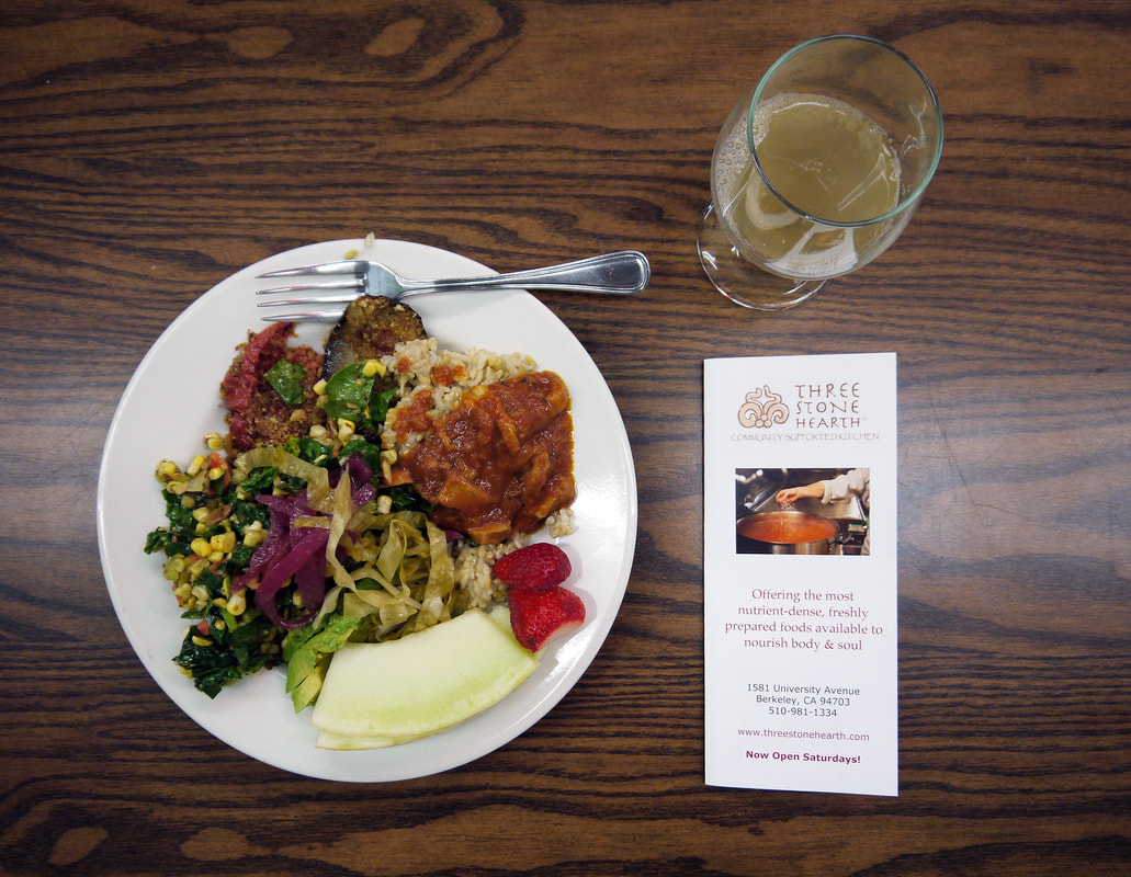 plate of food, cup of kombucha and pamphlet from three stone hearth in berkeley