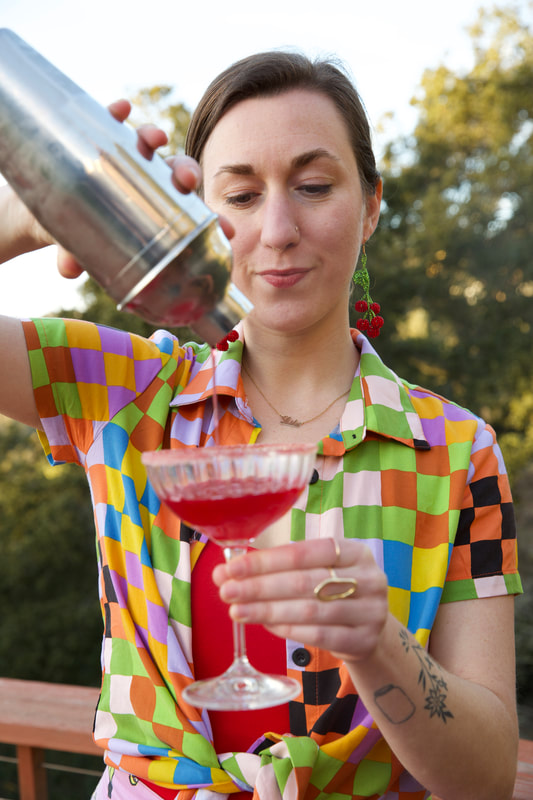 Woman in checkered shirt pouring mocktail into class during a private event in the bay area