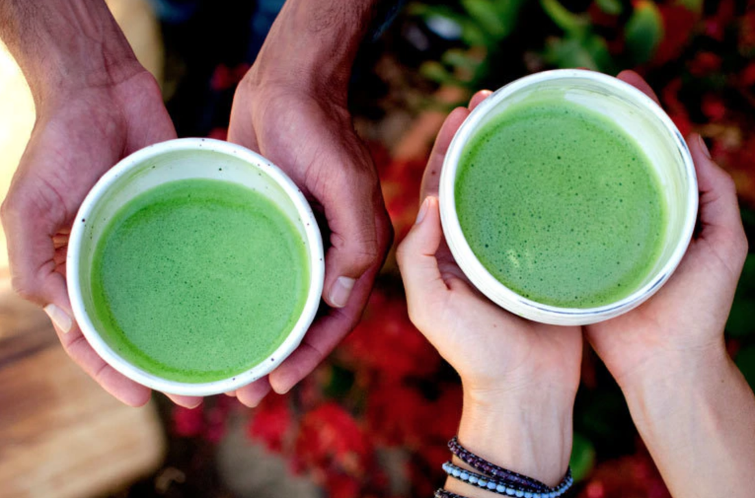 two sets of hands holding matcha tea
