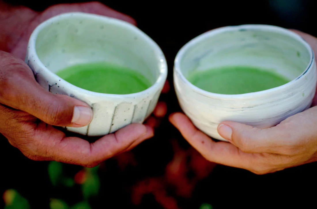 two sets of hands holding matcha tea side view