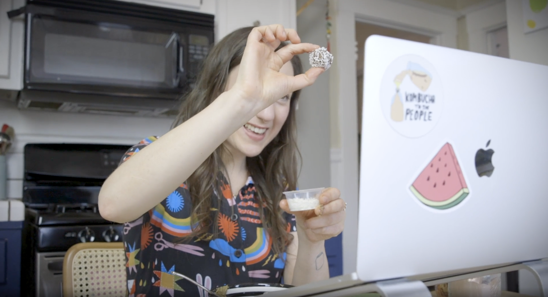 woman holding up superfood bite snack she made in a corporate hack your snacks virtual workshop