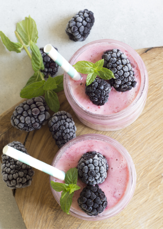 Superfood smoothie with blackberries, coconut and flowers ontop
