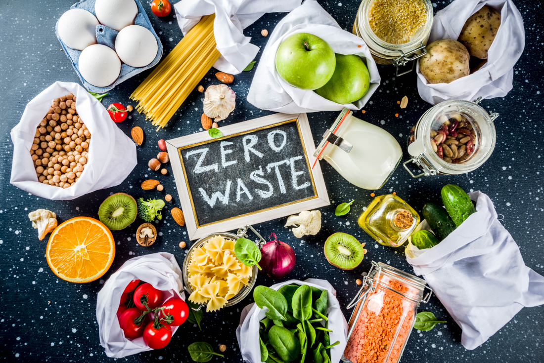 Blackboard that says Zero Waste with a variety of foods in sustainable bags scattered around